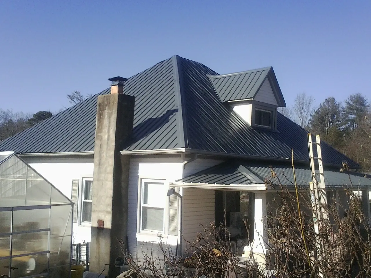 Dark blue standing seam metal roof on a white farmhouse with dormer — Slate & Tile Roof Repair by Roofing Brothers in Murrayville