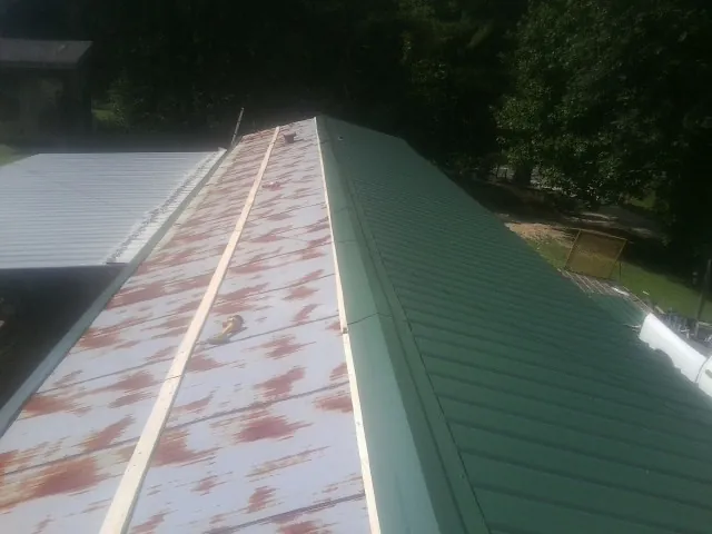 Old rusted panels beside newly installed green metal roofing — Wind Damage Roof Repair by Roofing Brothers in Murrayville