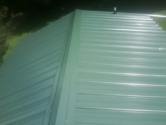 New green metal panels meeting at the ridge of a roof — Flat Roof Repair work by our crew in Murrayville