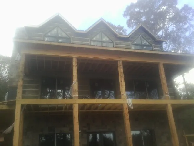Dormers and porch framing on a large log home under construction — Roof Coating work by our crew in Murrayville