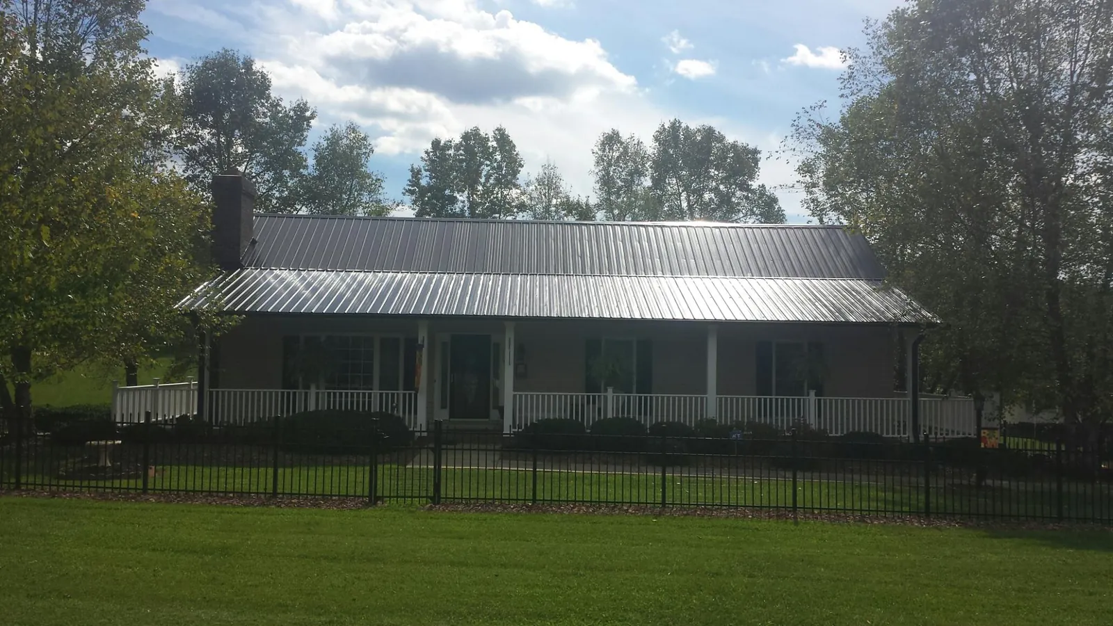 Gray metal roof on a brick ranch with a full width front porch — Gutter Guard Installation work by our crew in Murrayville