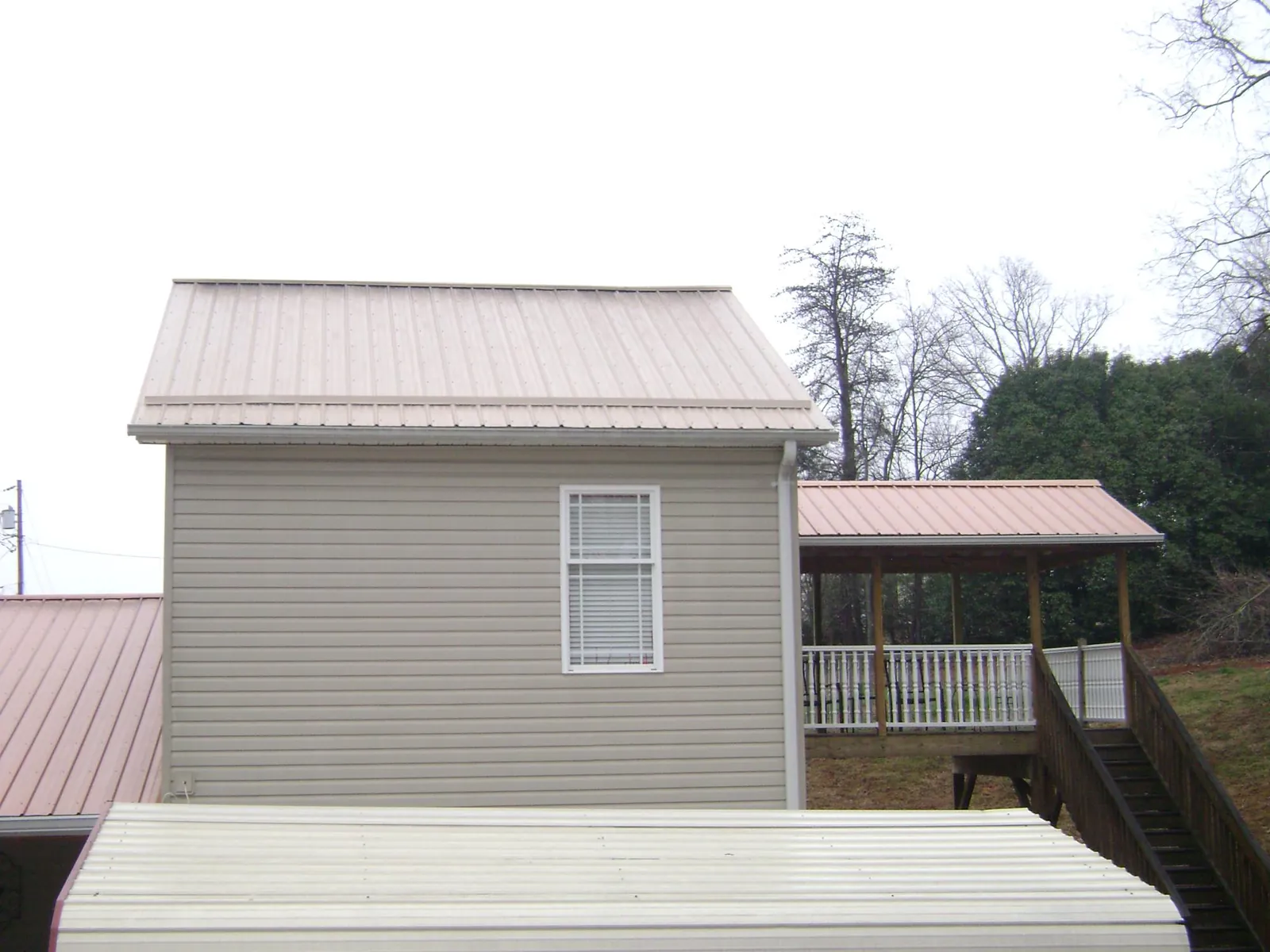 Tan metal roofs on a two story addition and attached porch, from a Roof Replacement job in Murrayville