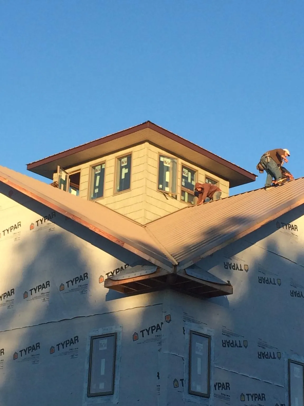 Roofers working around a rooftop cupola on a new metal roof at sunset — Roof Waterproofing in Murrayville by Roofing Brothers